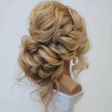 Chunky loose braided bun bridal hairstyle with soft messy texture and volume