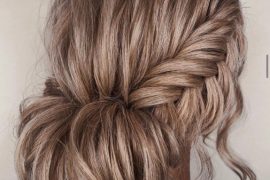 Bridal fishtail braid bun hairstyle with soft rolled bun and loose strands