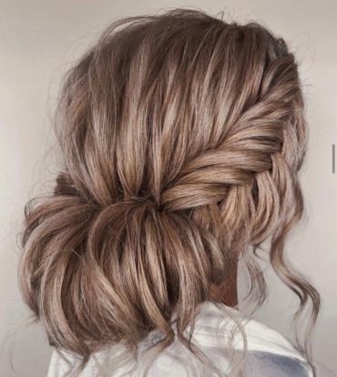Bridal fishtail braid bun hairstyle with soft rolled bun and loose strands