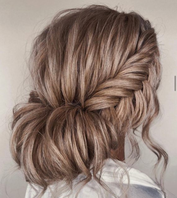 Bridal fishtail braid bun hairstyle with soft rolled bun and loose strands