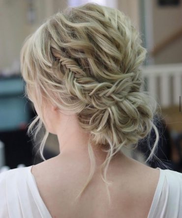 Small fishtail braided messy bun with textured waves – romantic bridal hairstyle