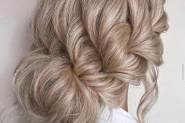 Textured braided bun with effortless volume and romantic blonde waves – ideal for brides
