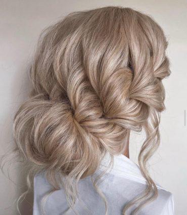 Textured braided bun with effortless volume and romantic blonde waves – ideal for brides