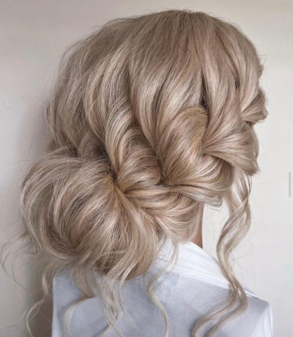 Textured braided bun with effortless volume and romantic blonde waves – ideal for brides