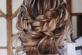 Romantic double braided messy bun bridal hairstyle with soft texture and volume