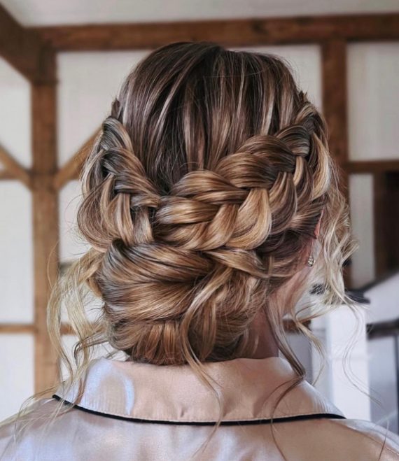 Romantic double braided messy bun bridal hairstyle with soft texture and volume