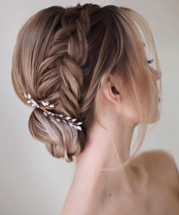 fStunning braided bun bridal hairstyle with side braid and floral hairpiece