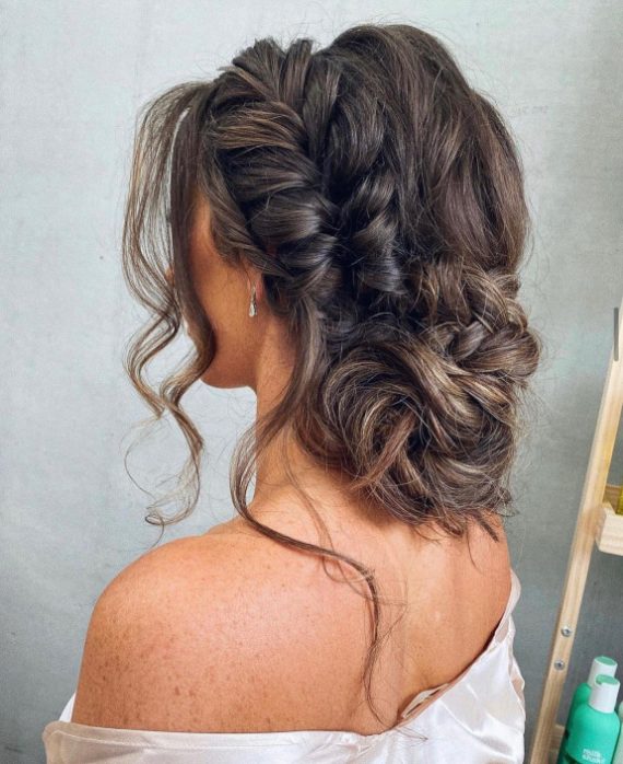 fChunky braided messy low bun with soft face-framing waves – romantic wedding hairstyle