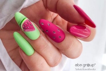 Almond-shaped nails with watermelon-inspired pink and green polish and seed nail art