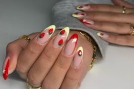 Almond-shaped nails with 3D cherry charms, strawberries, and daisy accents on nude base
