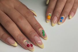 Almond nails with nude base, yellow French tips, and 3D sculpted fruits like cherries, oranges, and blueberries