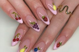 Almond-shaped pink nails with 3D cherries, lemons, grapes, strawberries, and blueberries on a nude base