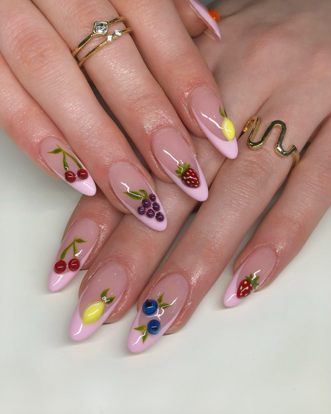Almond-shaped pink nails with 3D cherries, lemons, grapes, strawberries, and blueberries on a nude base