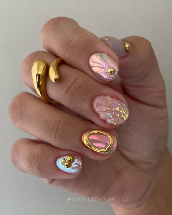 Short round nails with iridescent shell design, gold accents, pearls, pastel swirls, and abstract mermaidcore elements