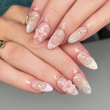 Almond-shaped nude nails with pink 3D starfish, white shell patterns, and gold accents, styled in a beach-inspired summer nail design.