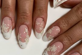 Almond-shaped bridal nails with nude pink base, white French tips, 3D floral accents, and rhinestones