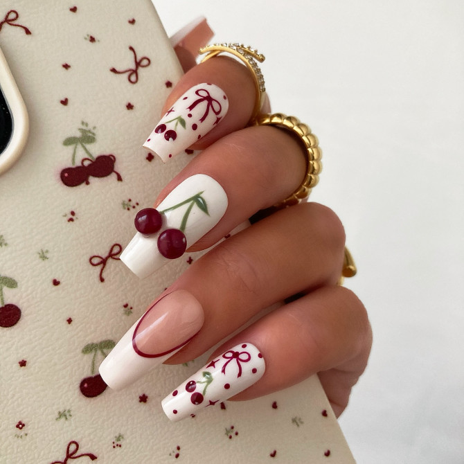 Long square nails with white base, 3D cherry accents, and red hand-painted bows and dots