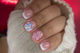 Short square nails with classic white French tips, one with pink 3D flower accent and another with colorful glitter flakes on a nude base.