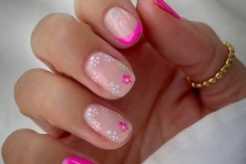 Short nails with hot pink French tips and white daisy floral designs on nude base