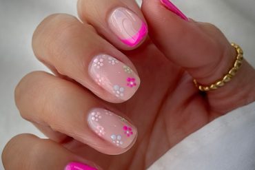 Short nails with hot pink French tips and white daisy floral designs on nude base
