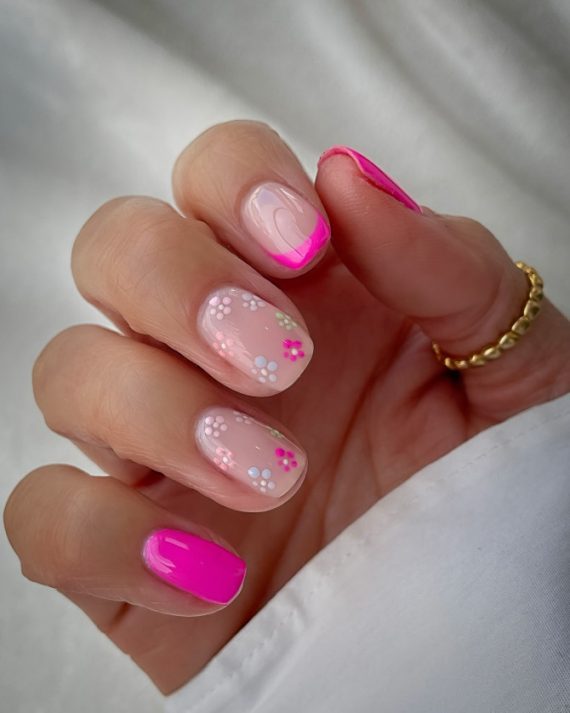 Short nails with hot pink French tips and white daisy floral designs on nude base