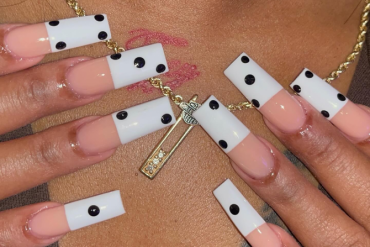 Long square acrylic nails with nude bases, white tips, and black dot accents inspired by domino tiles for a bold, graphic nail design.