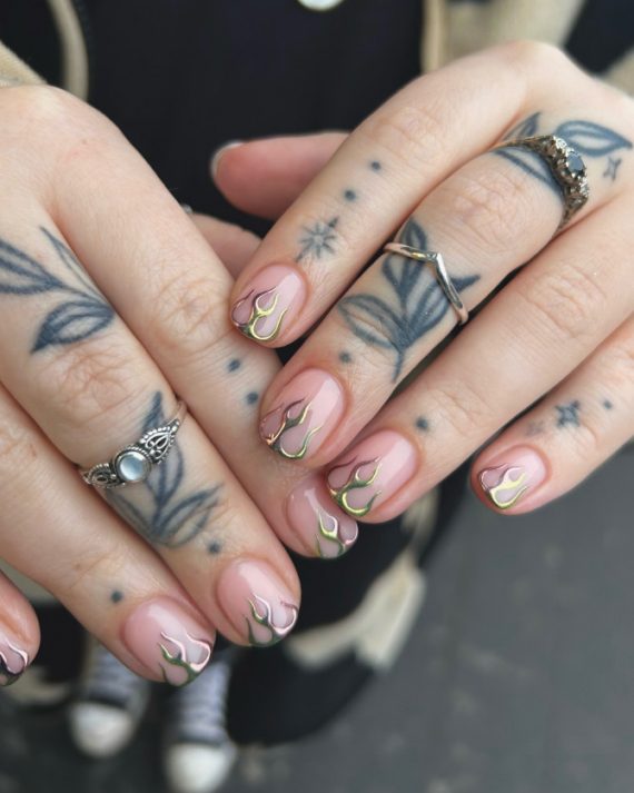 Short nude nails with iridescent chrome flame tips in gold and green hues