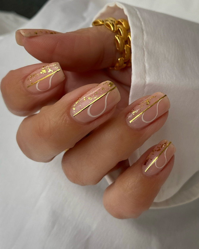 Short nude nails with gold foil, minimal white line art, and glossy finish