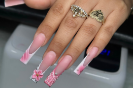 Long coffin nails in soft pink tones with mismatched 3D art, including flowers, plaid patterns, zebra print, and pearl embellishments.