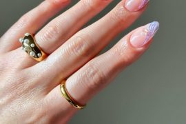 Almond-shaped nails with nude base, iridescent lilac waves, and small pearl accents