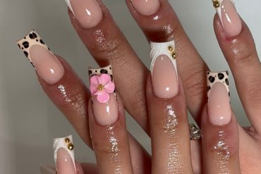 Coffin-shaped nails with nude base, leopard print French tips, 3D pink flowers, gold studs, and white swirl details.