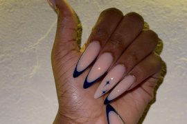 Nude almond-shaped nails with deep midnight blue French tips and a small celestial star accent