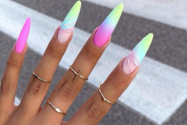 Long stiletto nails with neon ombre matte finish in pink, green, blue, and purple gradient, featuring swirl line art on two nails.