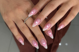 Almond-shaped nails with pink-to-white ombré gradient and small white heart accents on each nail, glossy finish.