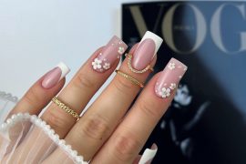 Square nude-pink nails with white French tips and 3D daisy floral accents on two fingers, decorated with tiny gold centers.