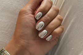 Short rounded nails with high-shine silver mirror chrome finish, worn with metallic bracelet