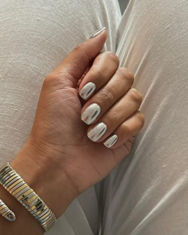 Short rounded nails with high-shine silver mirror chrome finish, worn with metallic bracelet