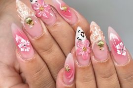 Medium stiletto nails with pink gradient, 3D flowers, seashell charms, and face art on translucent gel base