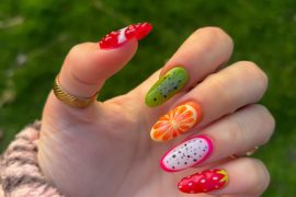 Oval nails with 3D fruit designs including strawberry, dragon fruit, orange, and kiwi in bright colors
