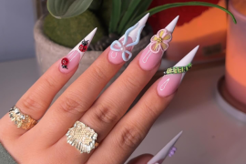 Long stiletto nails with pink and white base, decorated with 3D butterfly, flowers, ladybugs, gems, and nature-inspired designs.