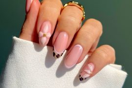 Almond-shaped blush pink nails with leopard French tips and white 3D floral accents