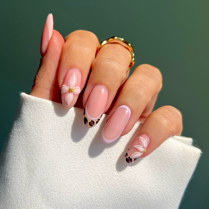 Almond-shaped blush pink nails with leopard French tips and white 3D floral accents