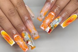 Long square acrylic nails with orange slices, white flowers, and Hello Kitty cartoon accents