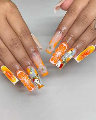Long square acrylic nails with orange slices, white flowers, and Hello Kitty cartoon accents