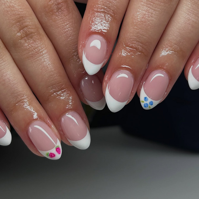 Almond-shaped French tip nails with soft pink base and miniature floral accents on two nails