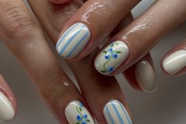 Short oval cream nails with blue vertical stripes and tiny blue floral accents