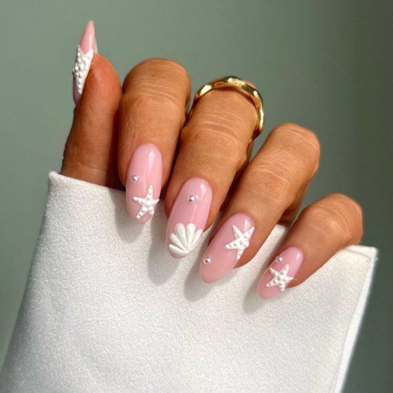 Glossy almond pink nails with 3D white starfish, seashell, and pearl accents