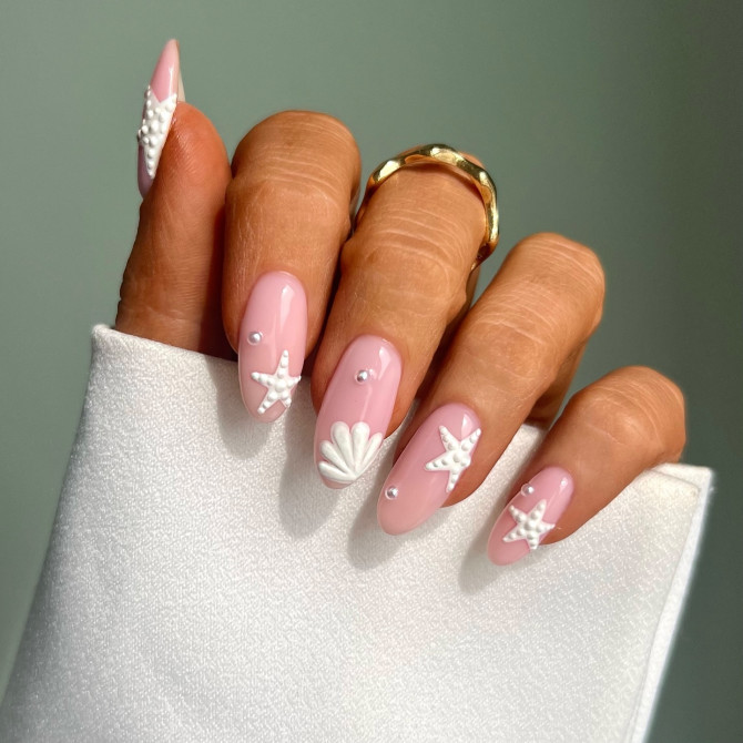 Glossy almond pink nails with 3D white starfish, seashell, and pearl accents