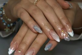 Almond nails with chrome swirls, pearlescent tips, nude base, and gold foil embellishments