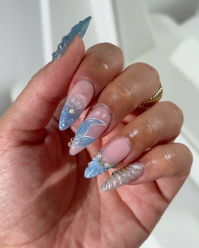 Long stiletto nails with chrome silver, blue jelly tips, and seashell textures on a pink-nude base